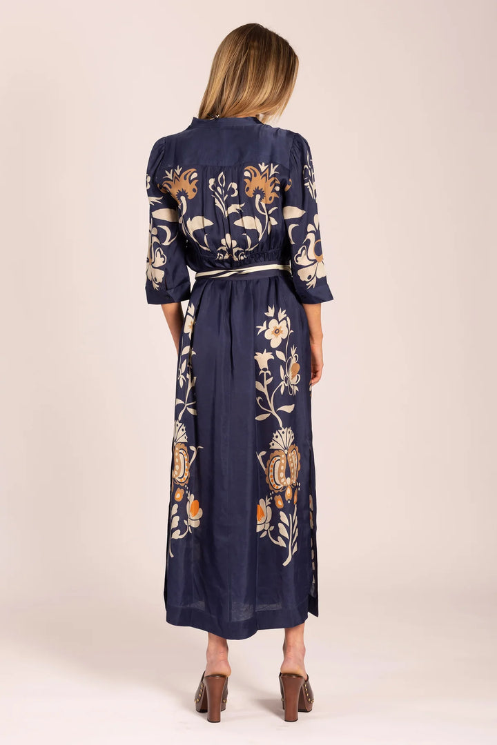 Navy dress with floral patterns worn by a person on a beige background