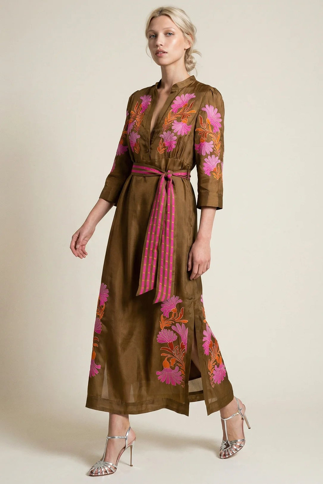 Woman wearing a brown dress with floral embroidery on a beige background