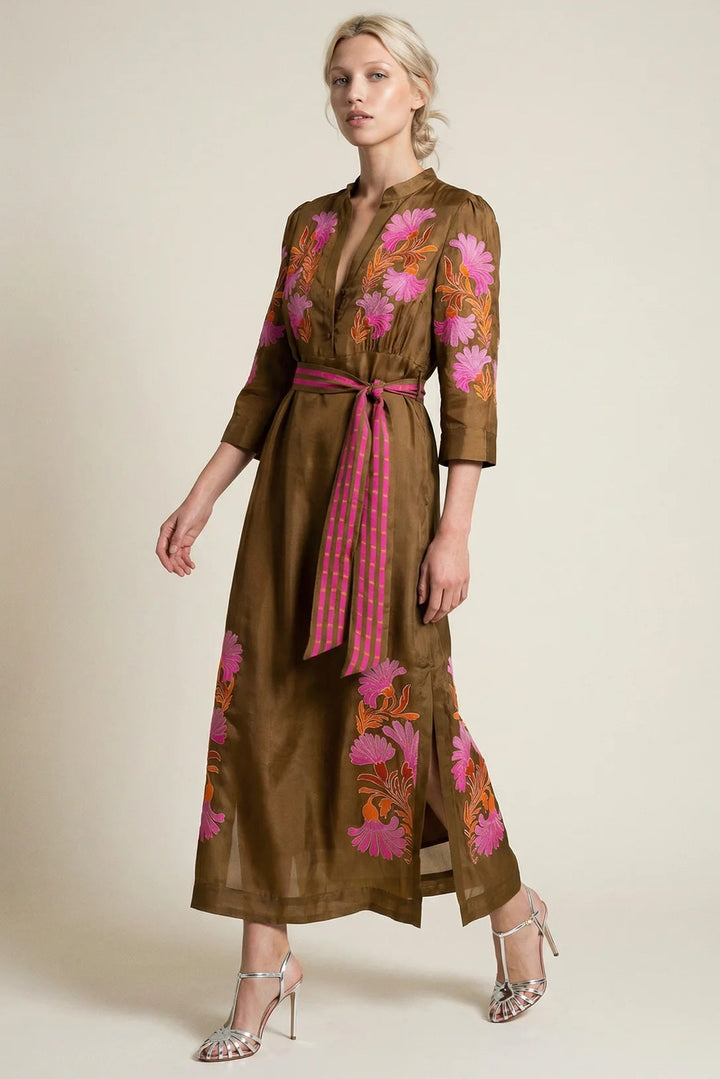 Woman wearing a brown dress with floral embroidery on a beige background