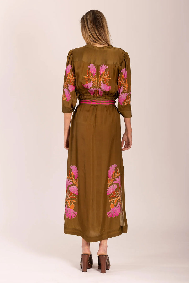 Woman wearing a brown dress with floral embroidery on a plain background