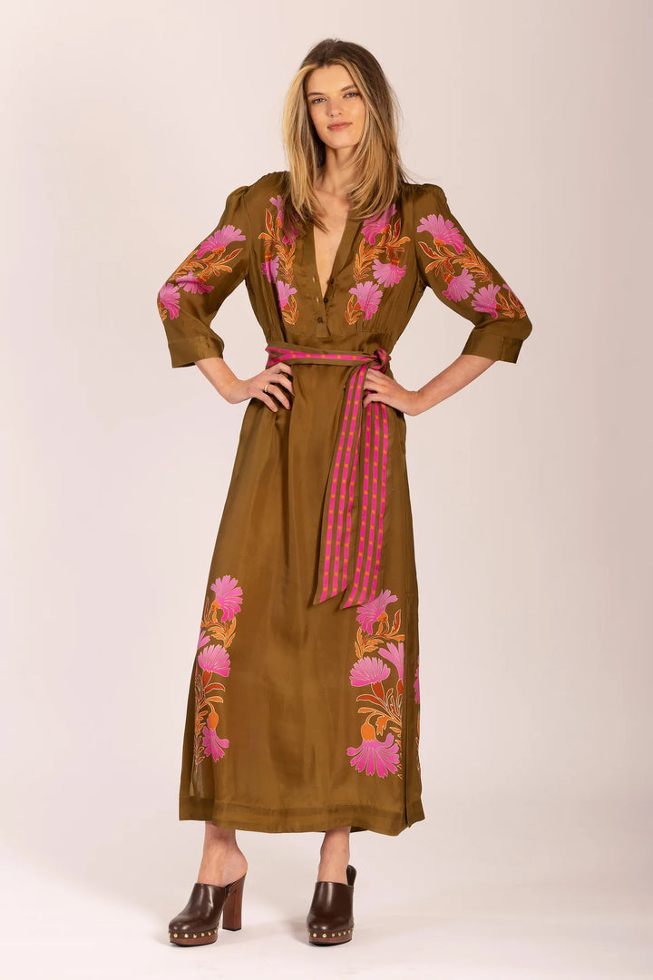 Woman wearing a brown dress with floral embroidery and a pink belt on a white background