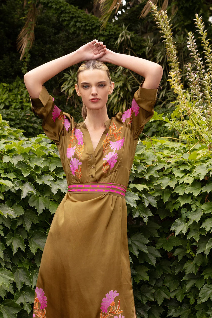 Woman wearing a brown dress with floral embroidery in a garden setting