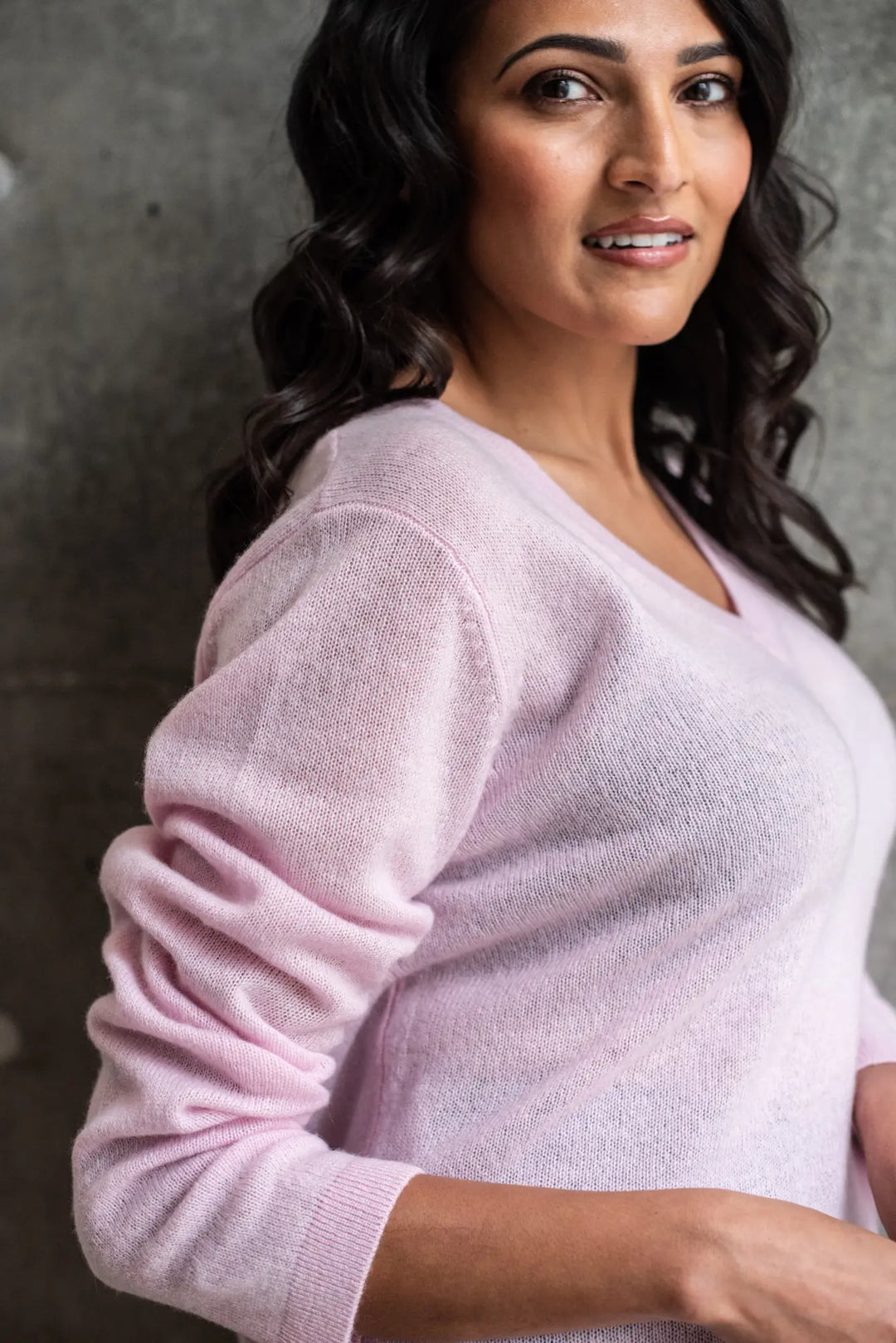 Woman wearing a light pink sweater against a gray background