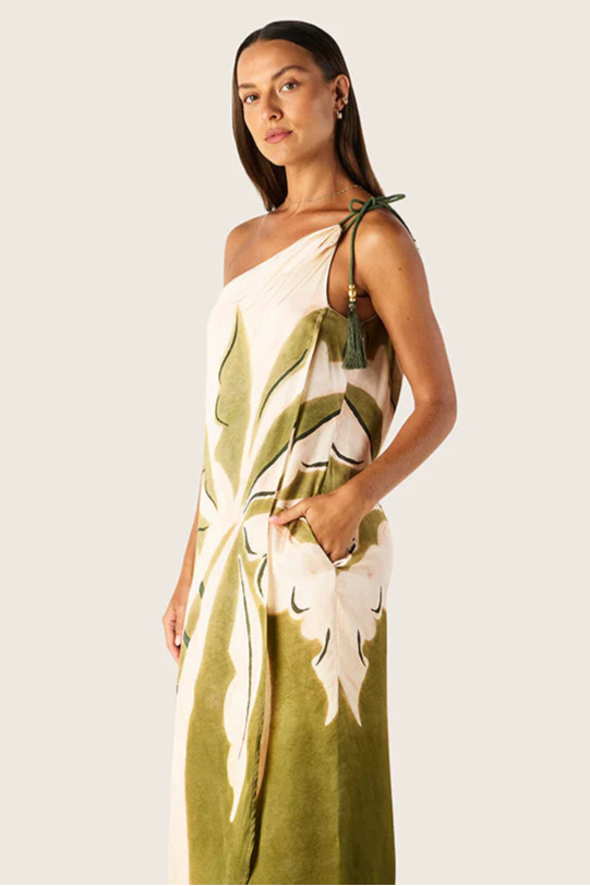 Woman wearing a green and white floral one-shoulder dress on a plain background