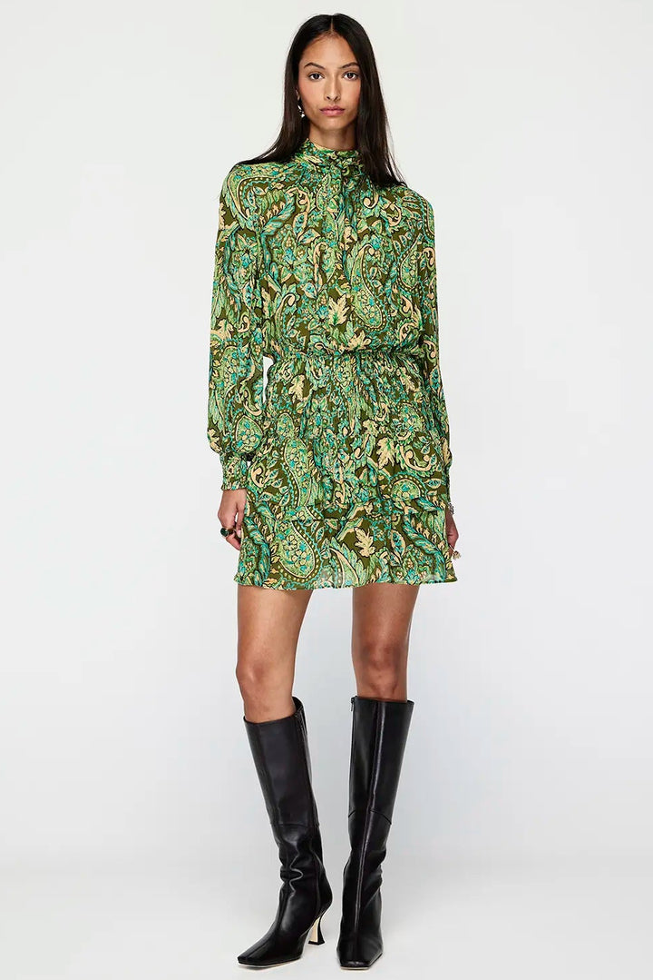 Woman wearing a green patterned dress with black knee-high boots on a white background
