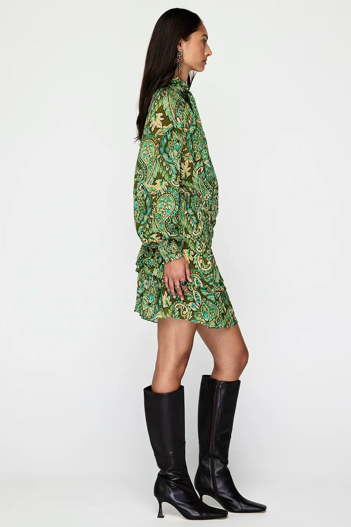 Woman wearing a green floral dress and black knee-high boots on a white background