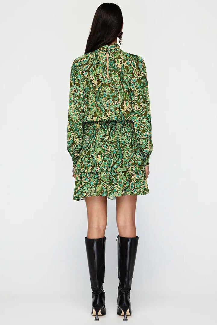 Woman wearing a green patterned dress with black boots on a white background