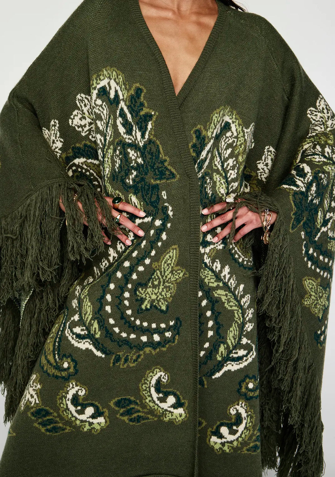 Green embroidered cardigan with fringe details on a white background