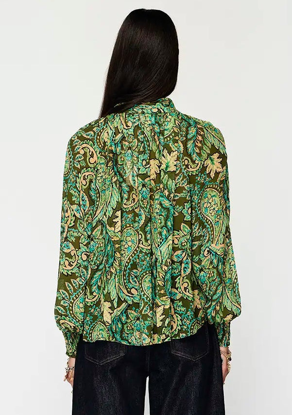 Person wearing a green floral blouse and black pants on a white background