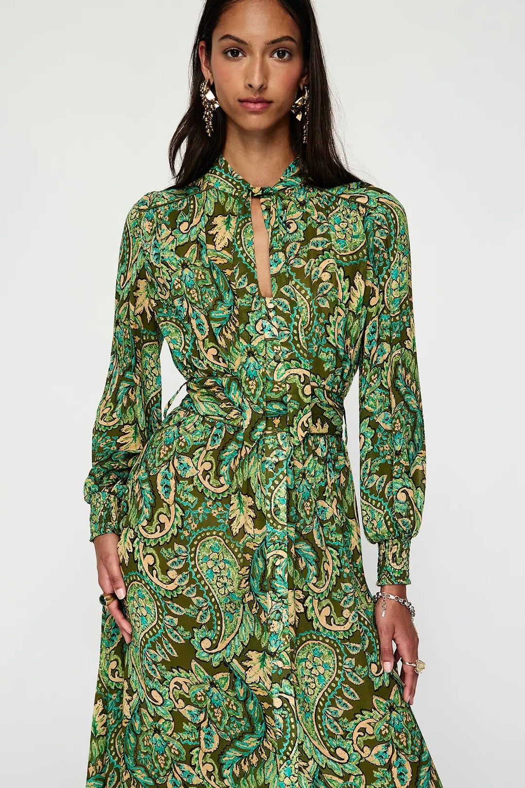 Woman wearing a green paisley dress against a white background