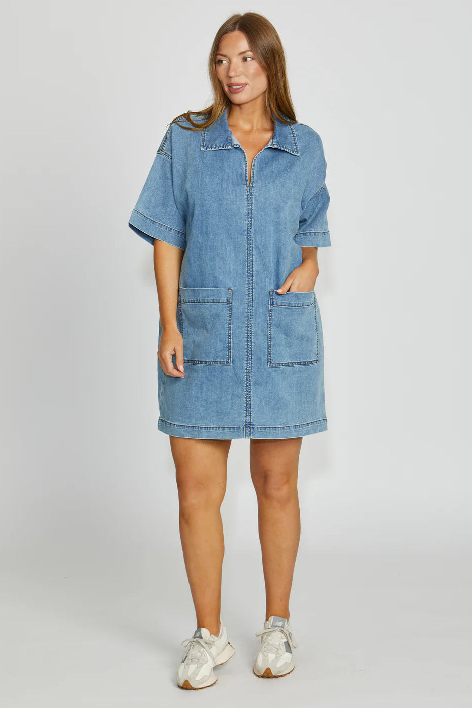 Woman wearing a denim dress on a plain background