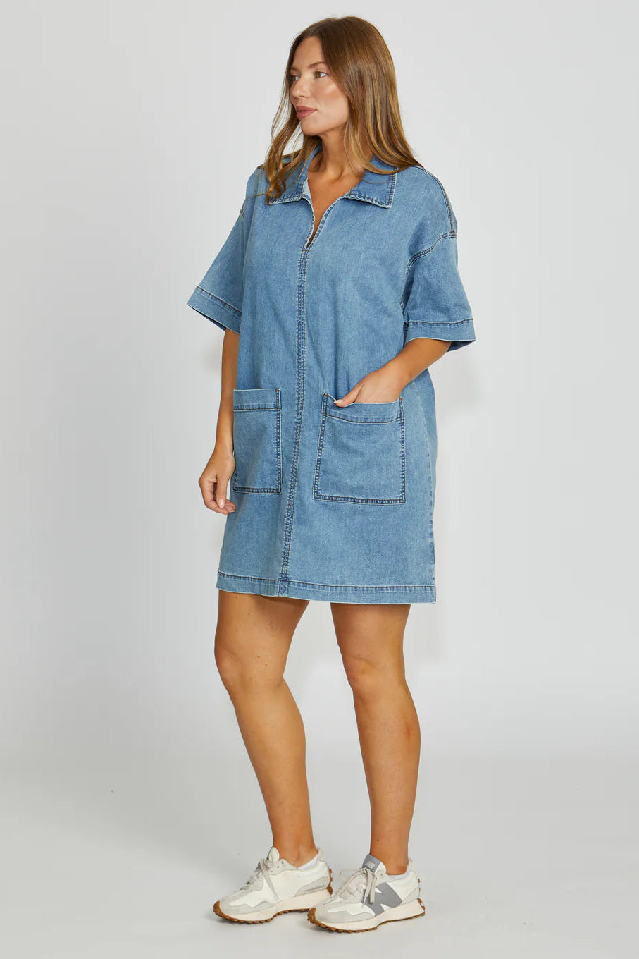 Woman wearing a blue denim dress on a white background