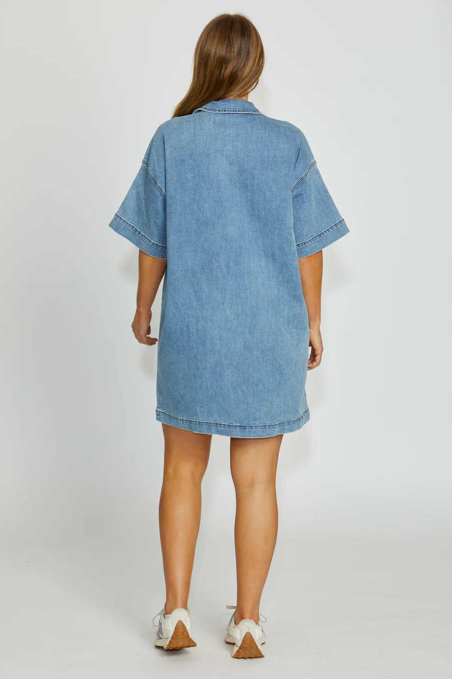Woman wearing a blue denim dress on a white background