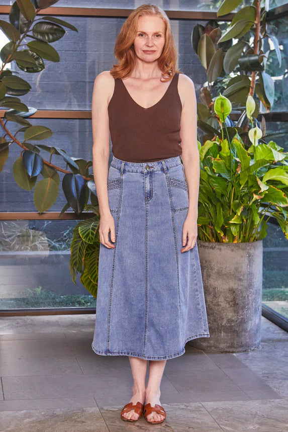 Woman standing indoors with plants in the background