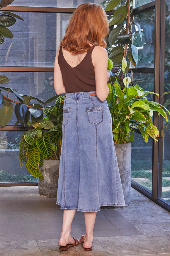 Woman standing in a room with large windows and indoor plants