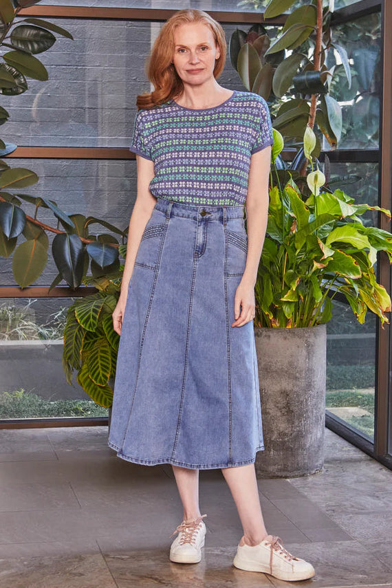 Woman in a blue dress standing in a modern indoor setting with plants.