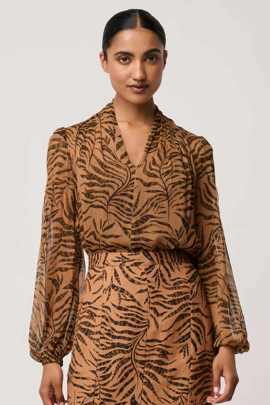 Woman wearing a brown and black patterned outfit on a white background