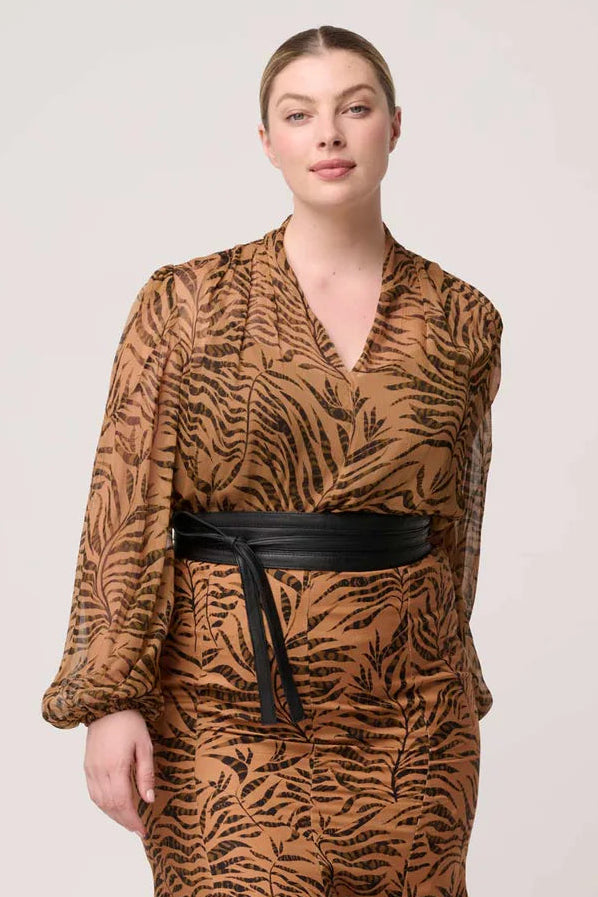 Woman wearing a brown animal print dress with a black belt on a white background