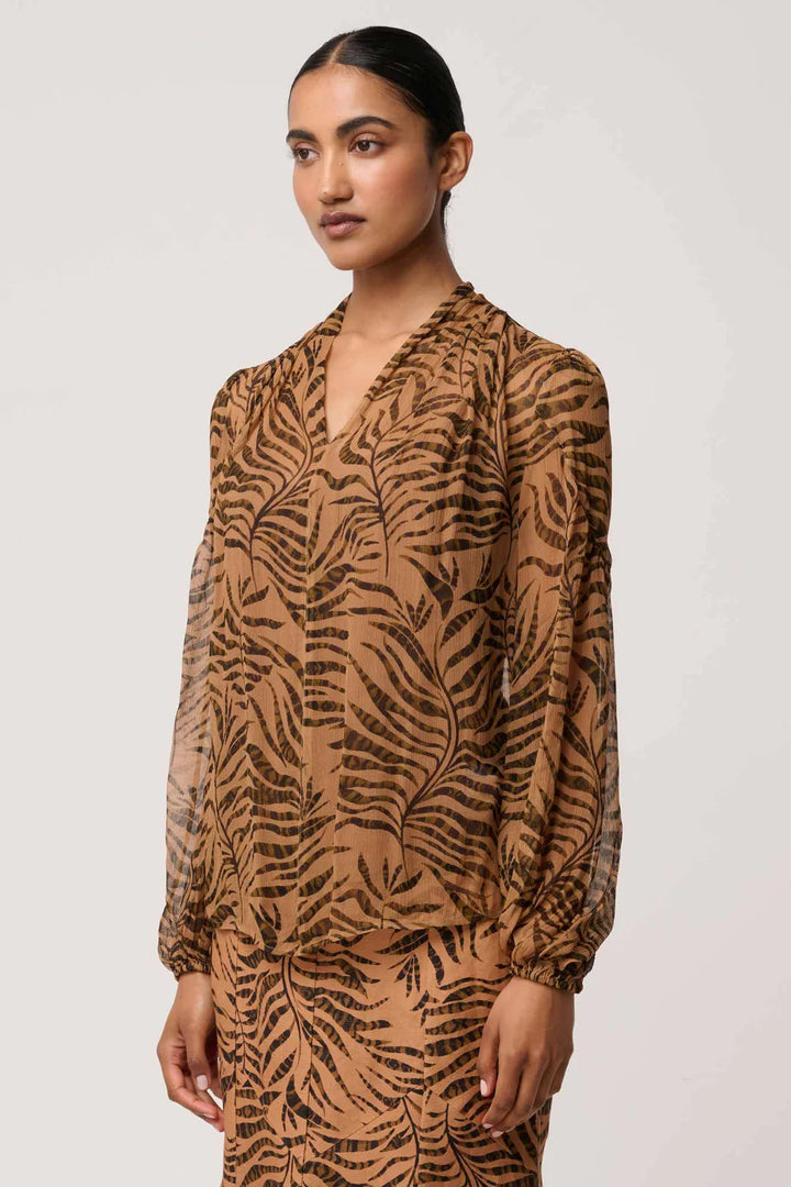 Woman wearing a brown dress with leaf pattern against a white background