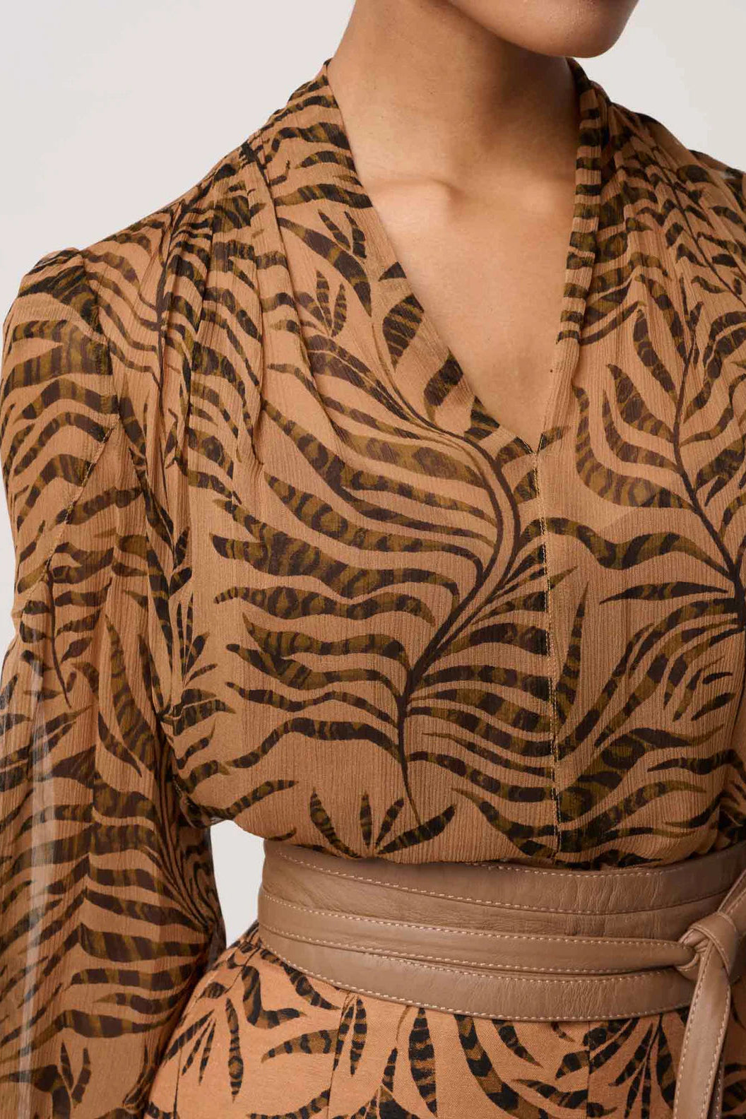 Brown patterned top with long sleeves on a neutral background