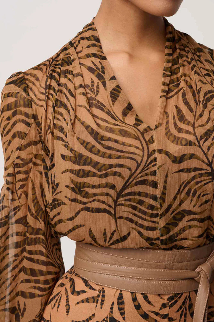 Brown patterned top with long sleeves on a neutral background
