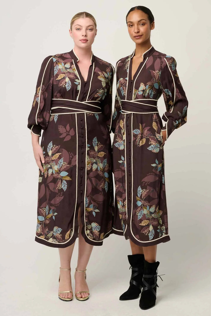 Two women wearing matching floral-patterned dresses on a white background