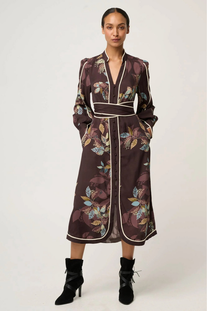 Woman wearing a floral patterned dress with a belt on a white background