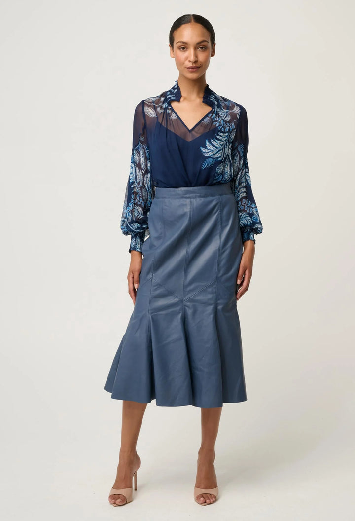 Woman wearing a blue floral blouse and blue skirt on a white background