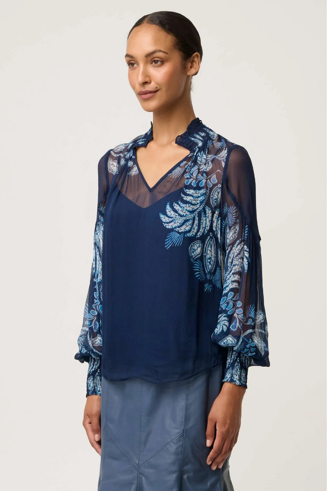 Woman wearing a blue blouse with floral embroidery on a white background