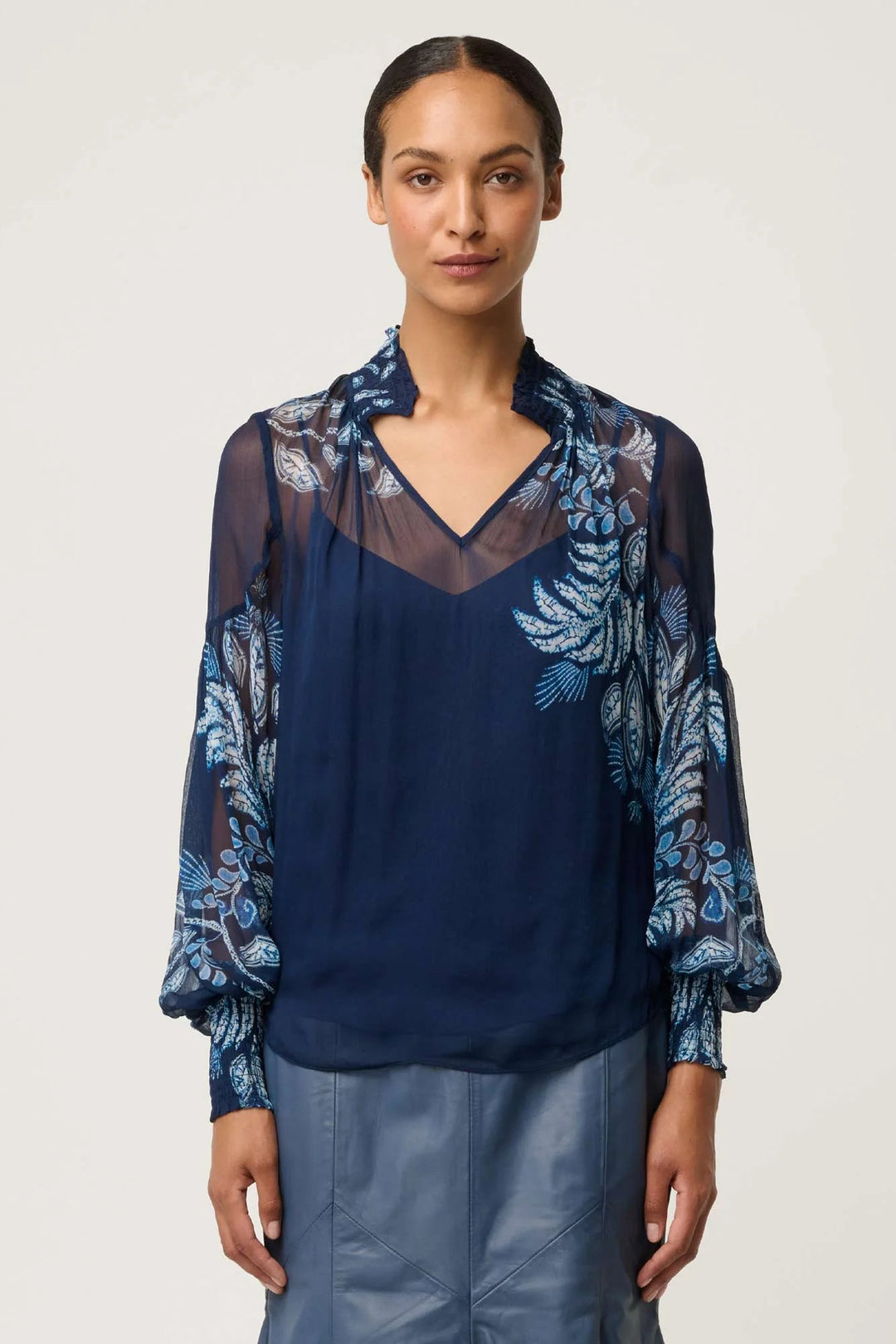 Woman wearing a navy blue blouse with floral patterns on a white background