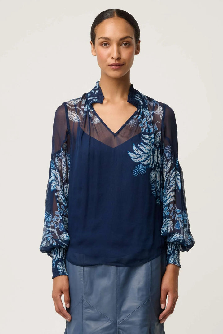 Woman wearing a navy blue blouse with floral patterns on a white background