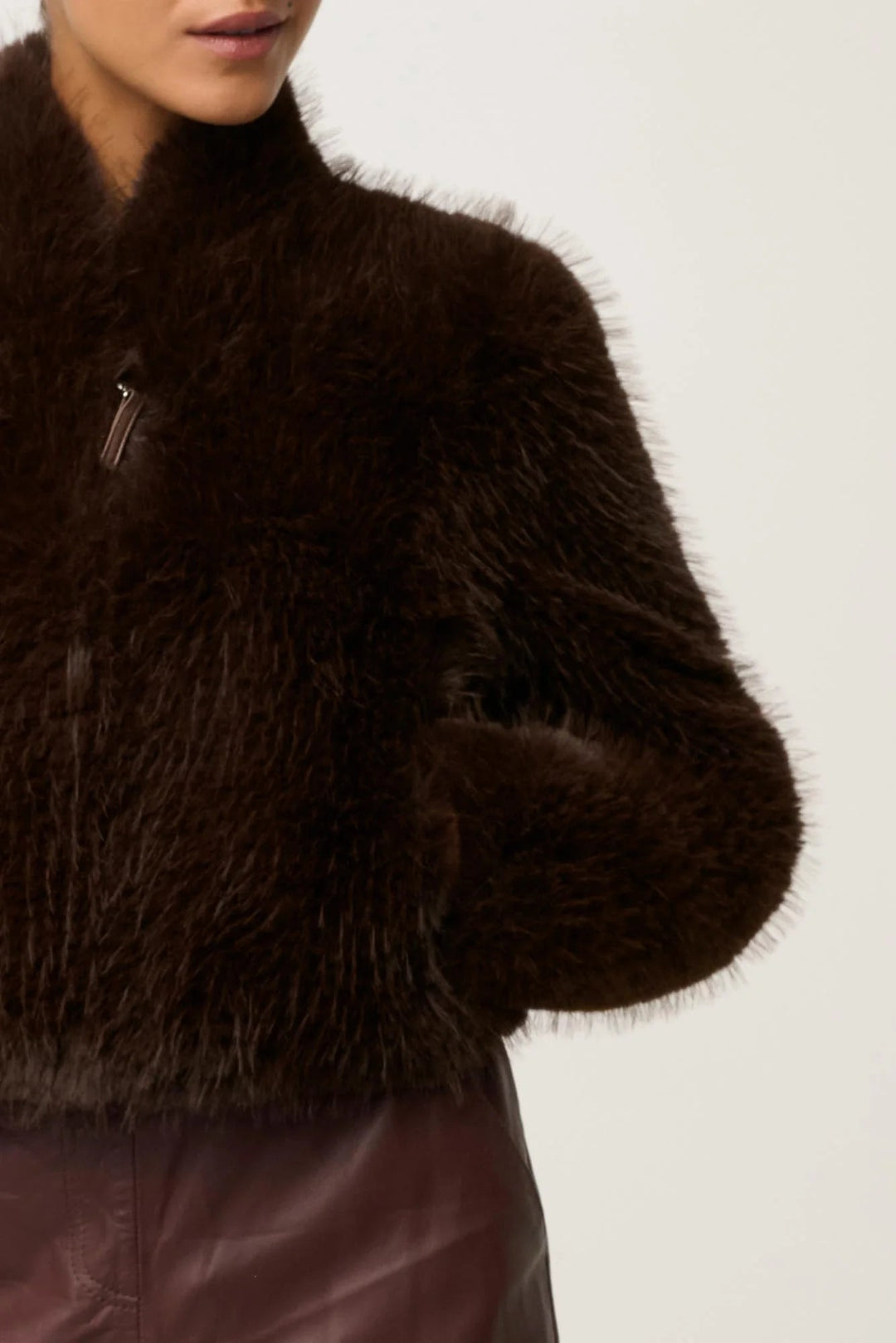 Brown fuzzy jacket worn by a person on a white background