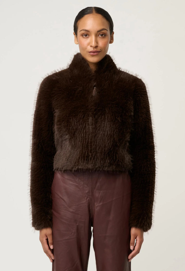 Woman wearing a brown fuzzy jacket and pants on a white background