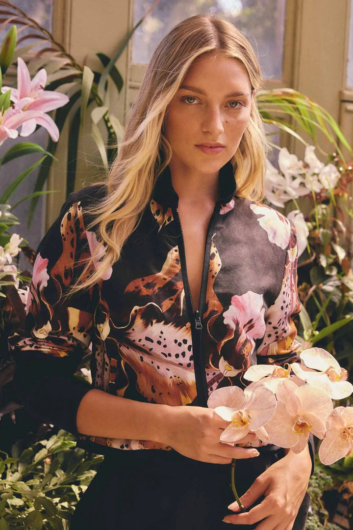 Woman in a floral jacket holding flowers in a garden setting
