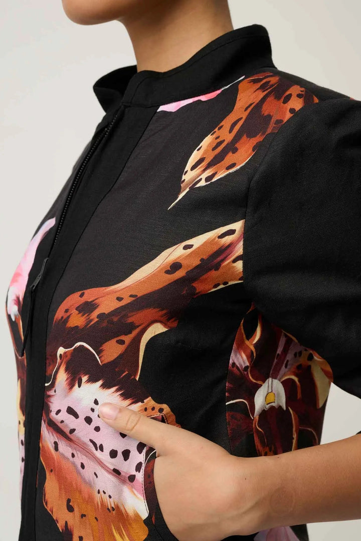 Close-up of a model wearing a black short-sleeve top with a bold orange, brown, and pink abstract floral print.