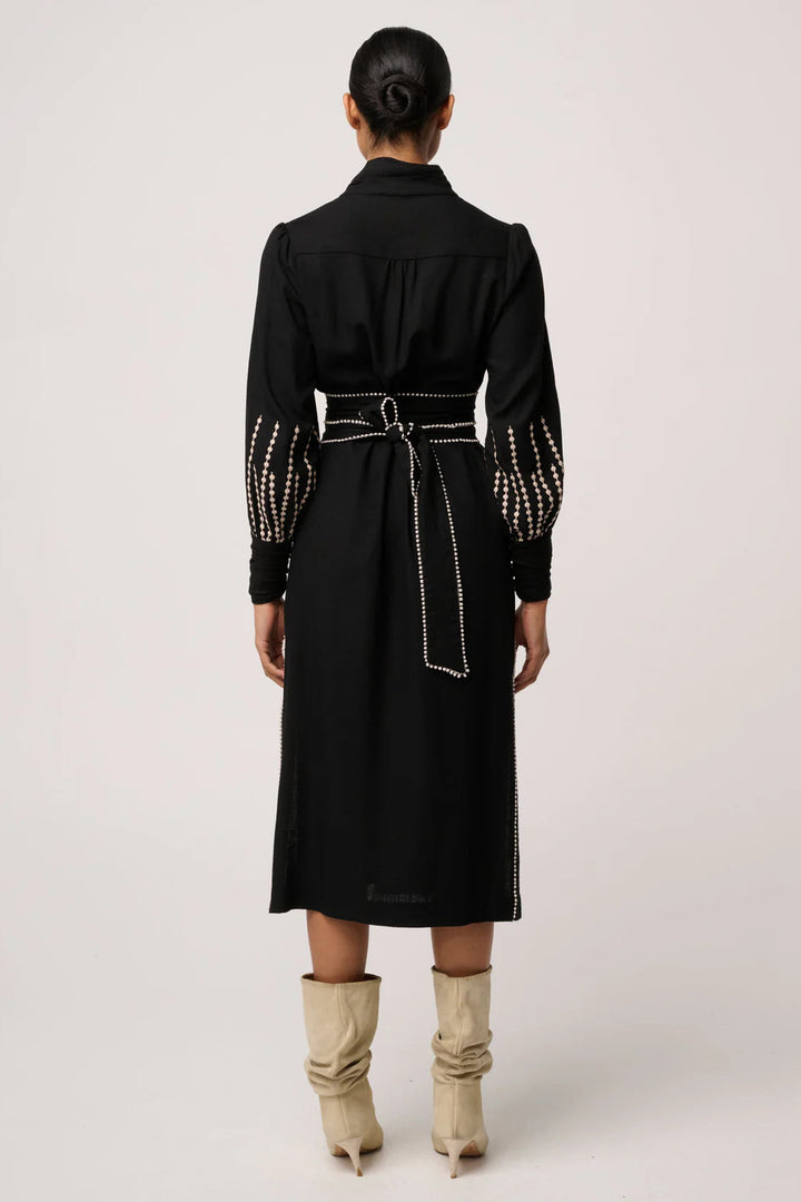 Person wearing a black dress with studded details on a white background