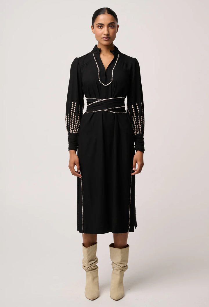 Woman wearing a black dress with studded details on a white background