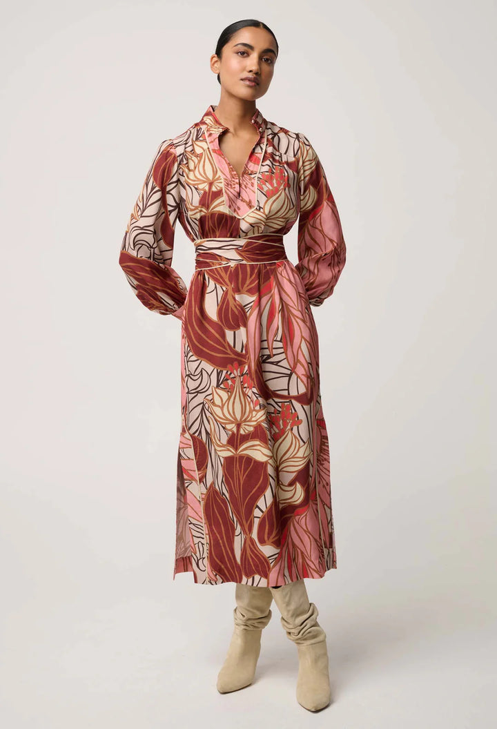 Woman wearing a patterned dress with beige boots on a white background