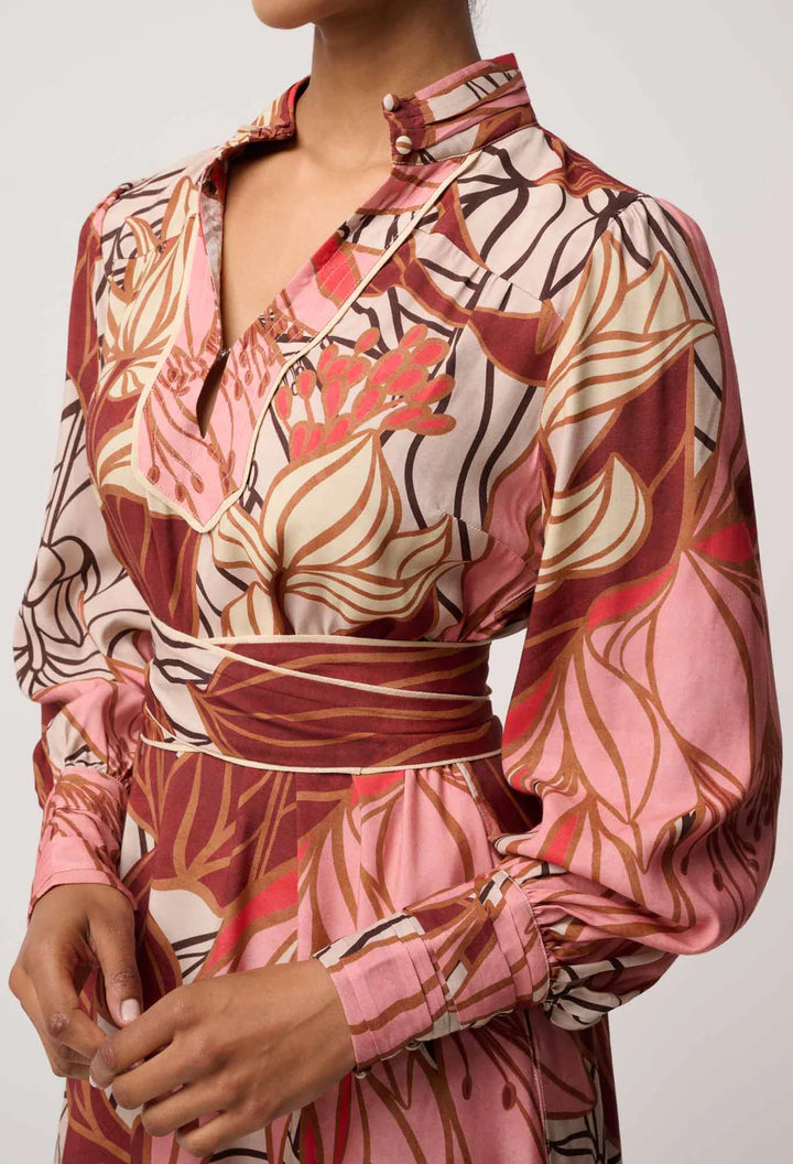 Patterned dress with long sleeves and a belt on a plain background