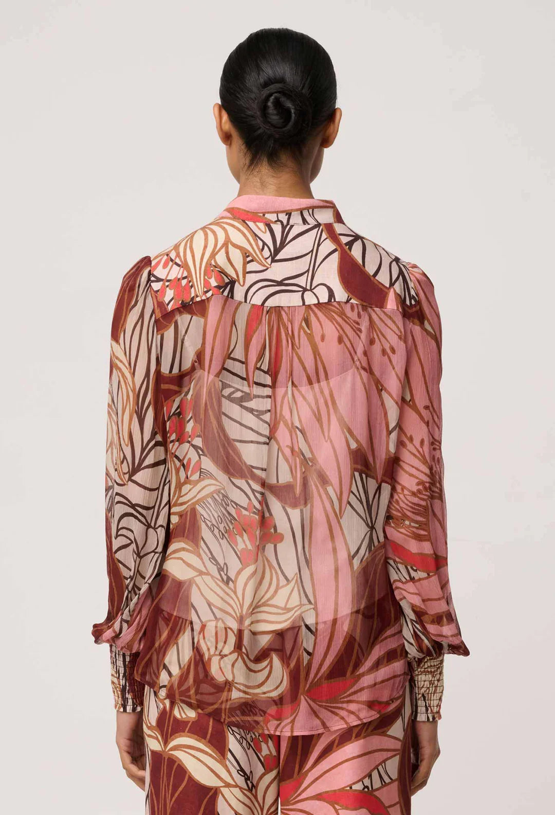 Woman wearing a patterned dress with long sleeves on a plain background