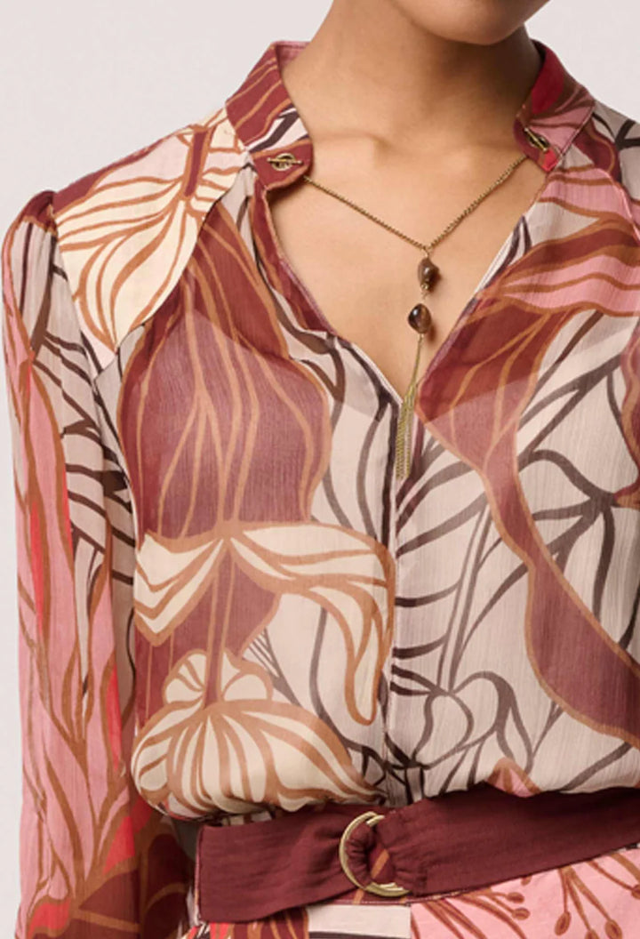Close-up of a person wearing a patterned blouse with a necklace.