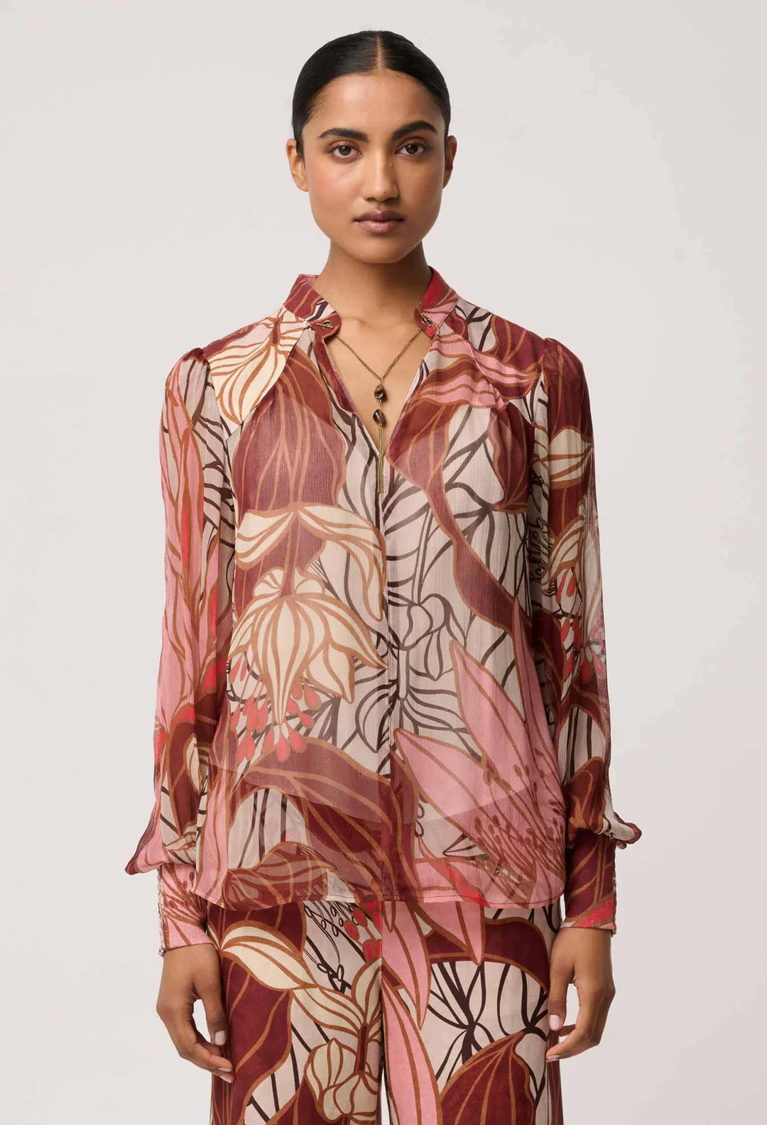 Woman wearing a patterned blouse against a plain background