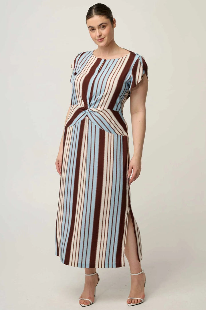A woman modeling a midi dress with vertical stripes in brown, beige, and light blue, featuring a twisted waist detail and cap sleeves, set against a plain light gray studio background.