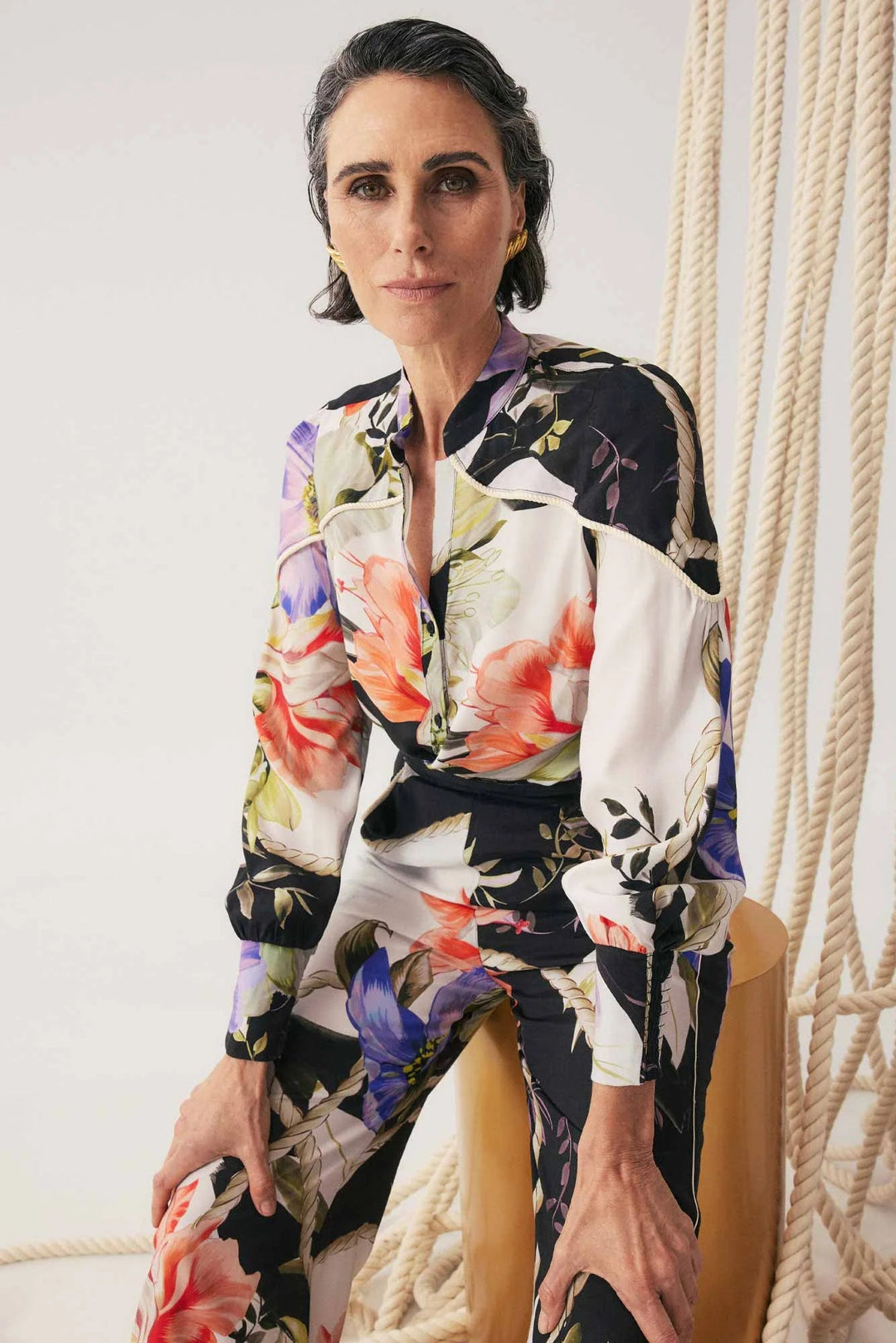 Woman wearing a colorful floral dress sitting on a chair.