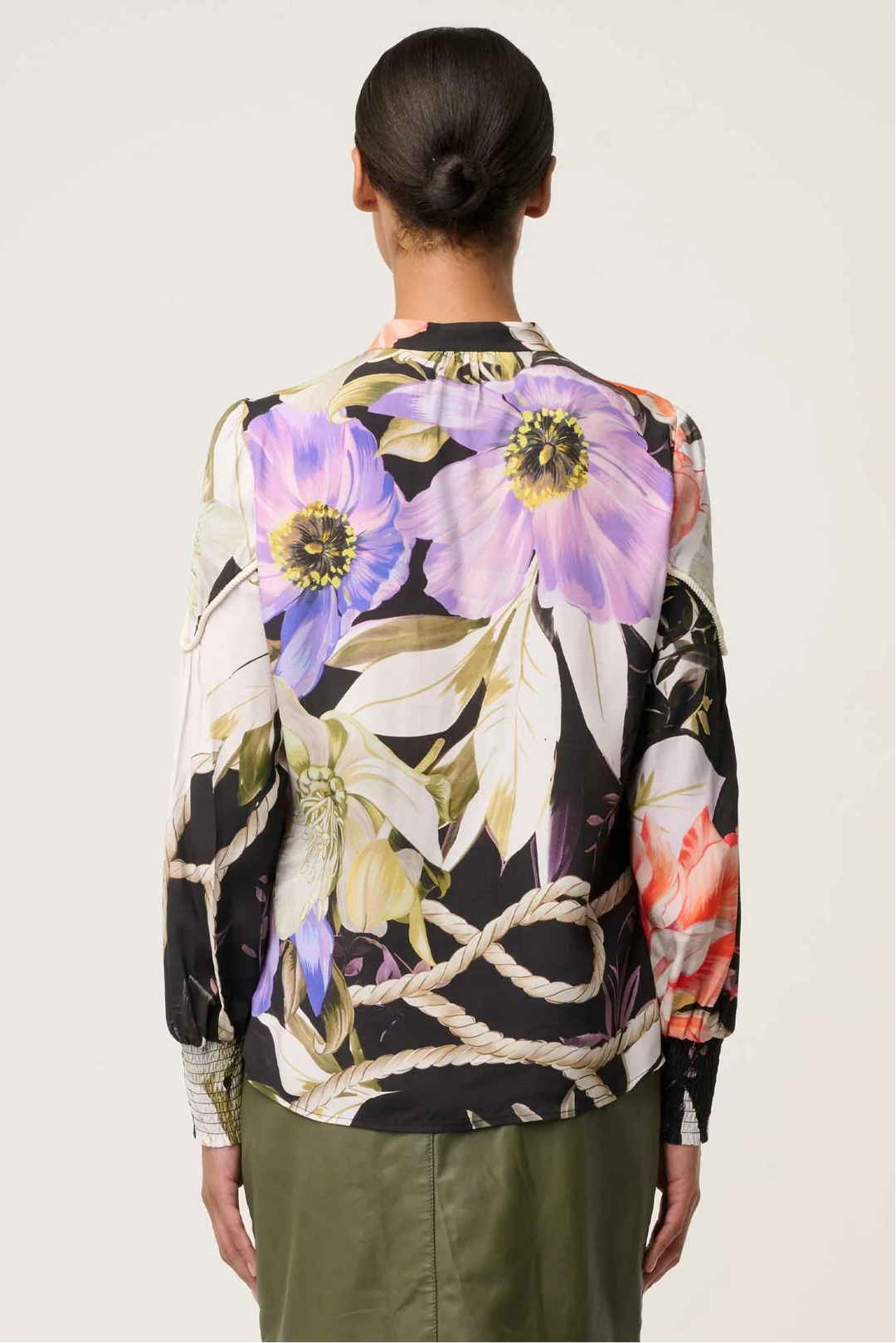 Person wearing a floral patterned shirt with a neutral background