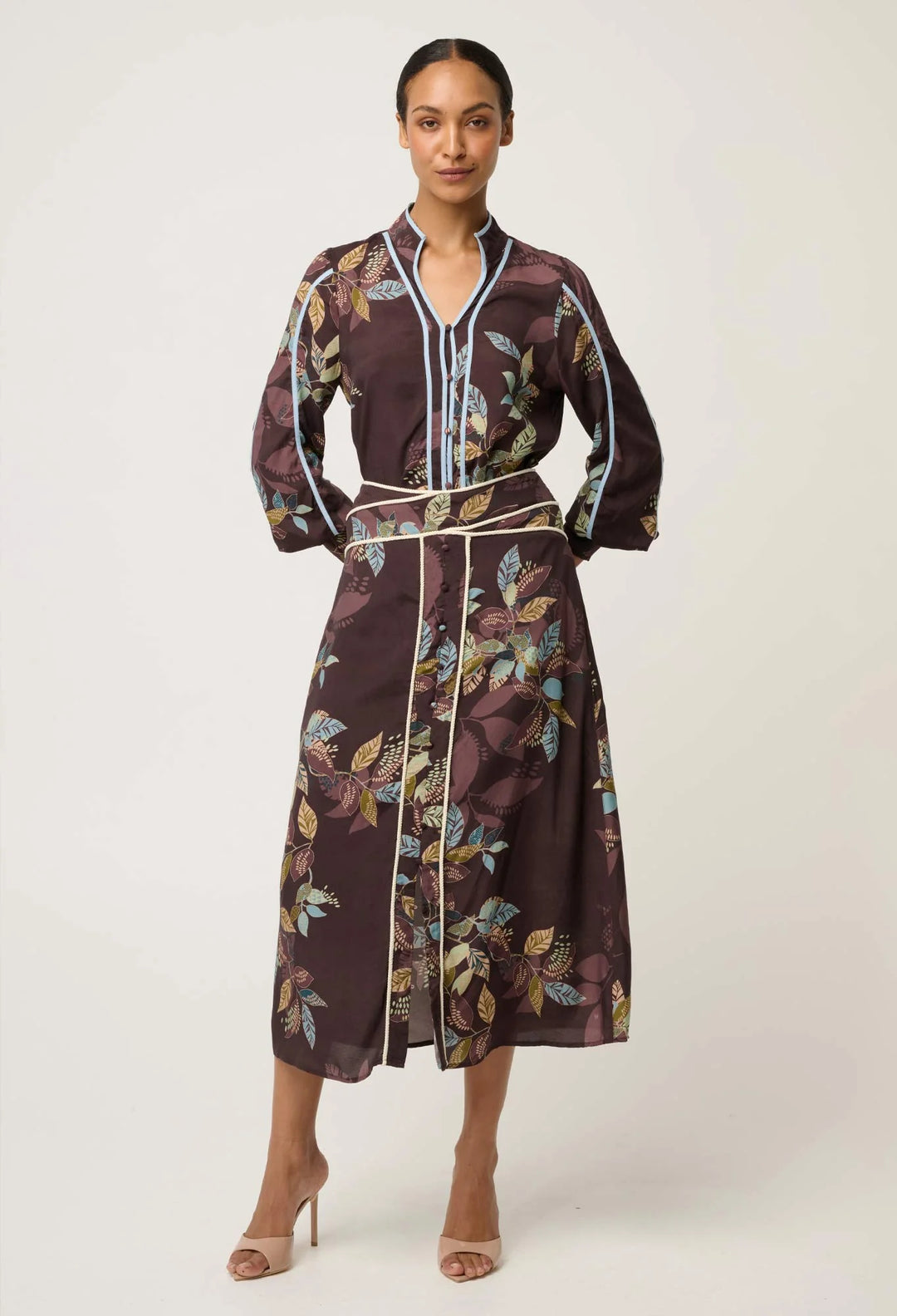 Woman wearing a patterned dress with a belt on a white background