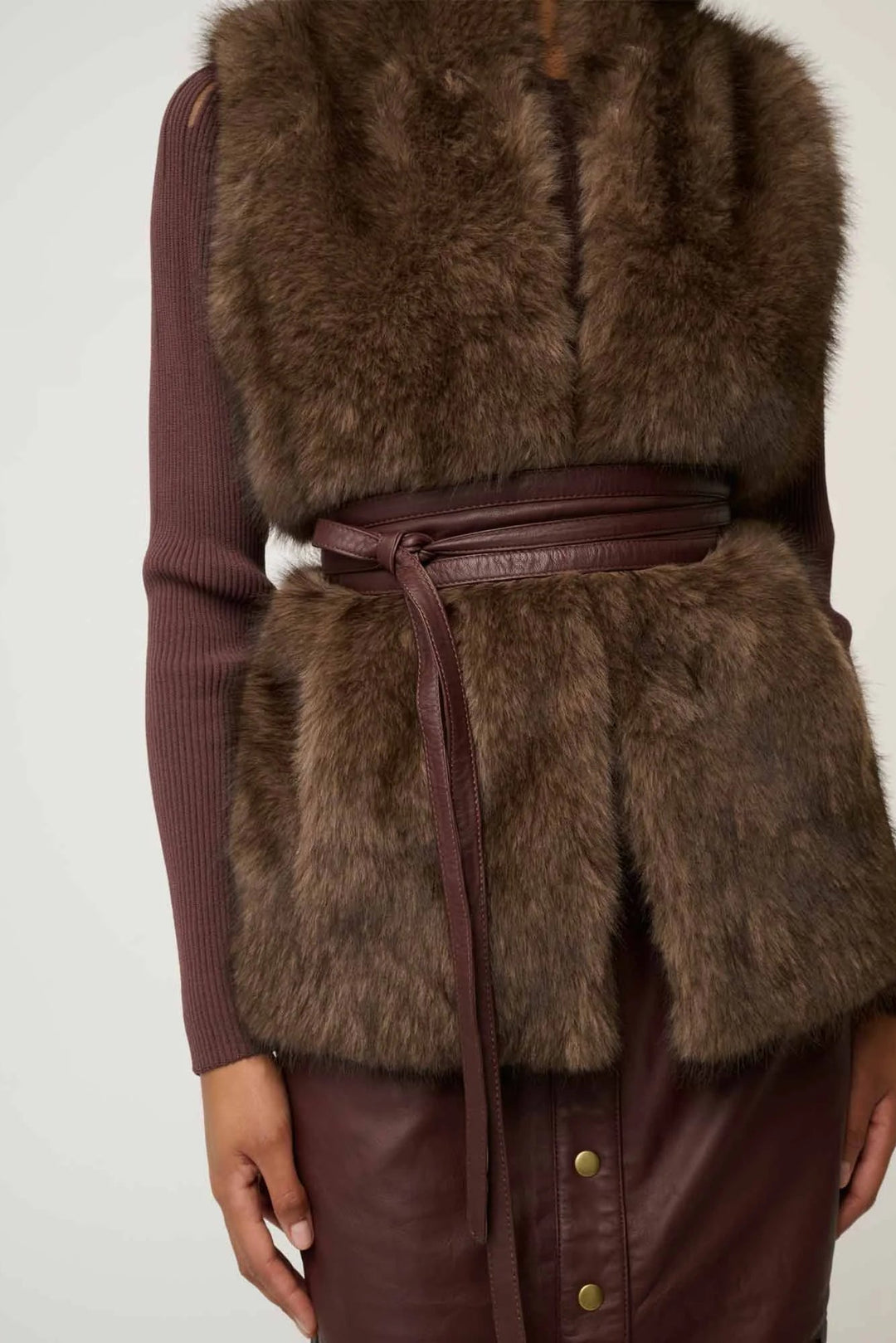 Brown fur vest with leather accents on a plain background