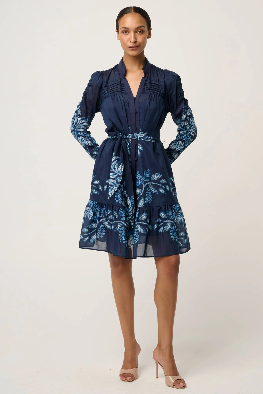 Woman wearing a navy dress with floral pattern on a white background
