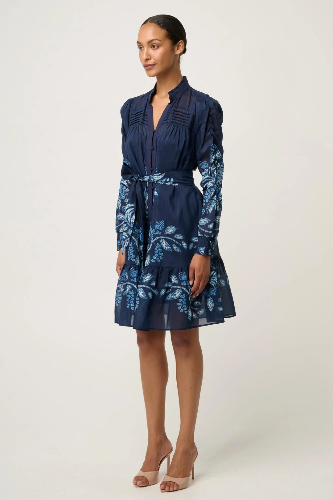 Woman wearing a navy blue dress with floral pattern on a white background