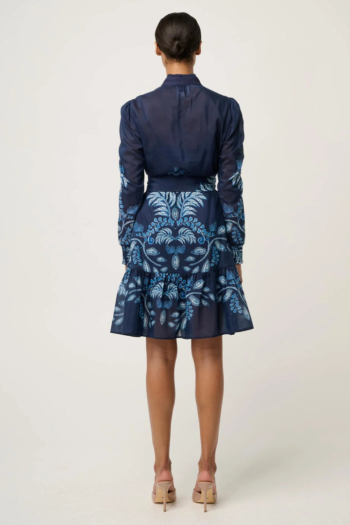 Person wearing a navy blouse and patterned skirt on a white background